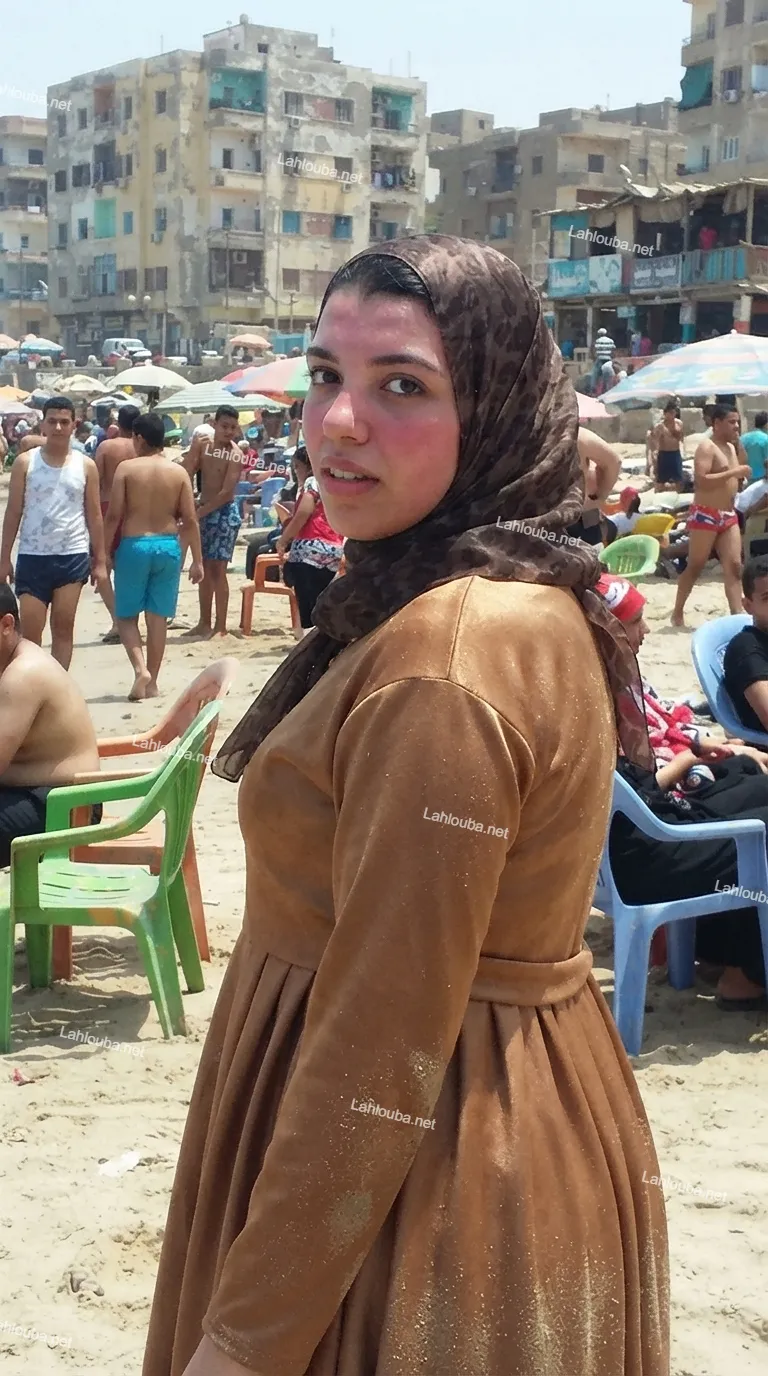 فتاة محجبة ترتدي عباية بنية على الشاطئ