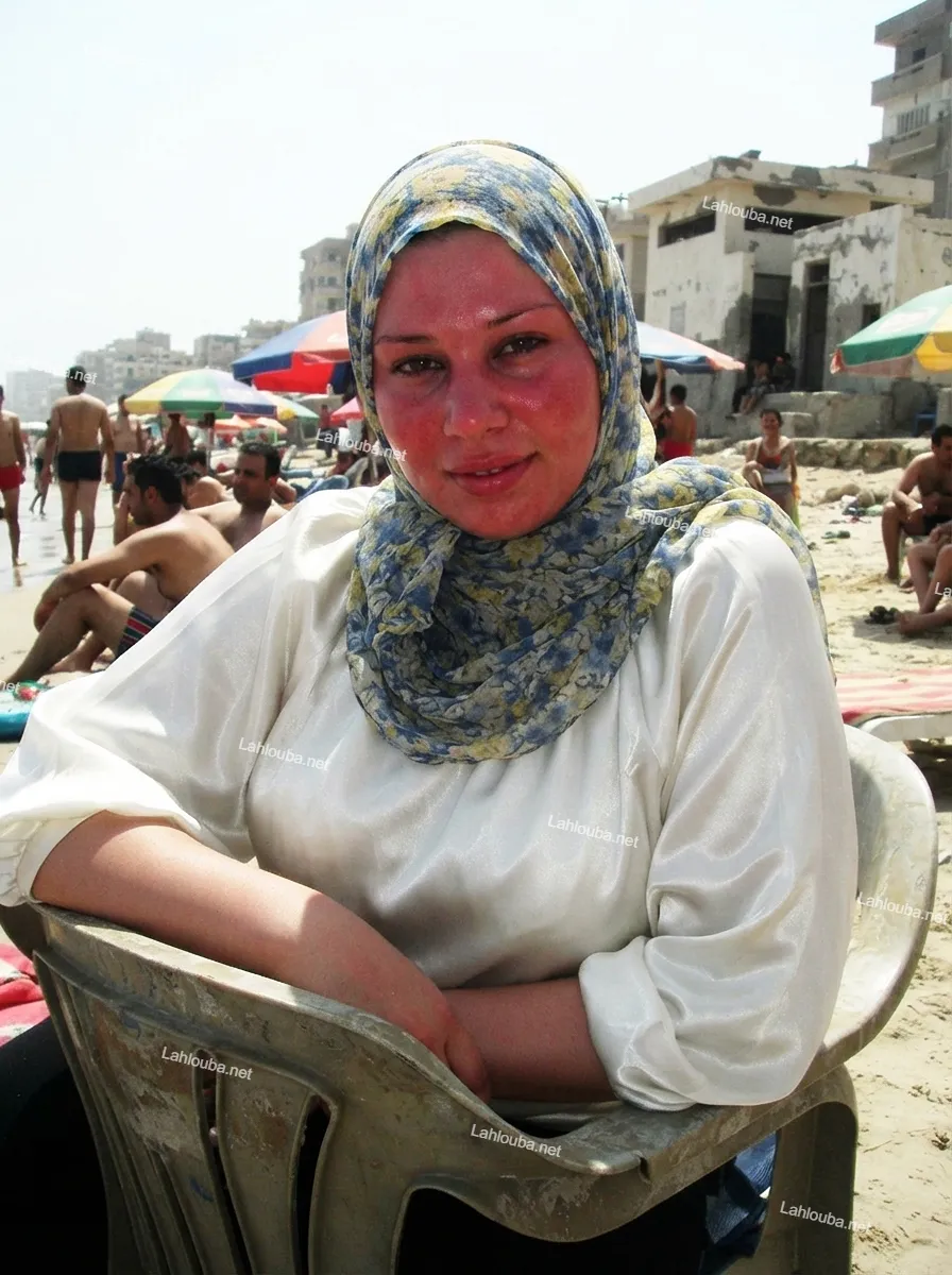 شابة مصرية ترتدي حجاب أزرق وأصفر فاتح وبلوزة بيضاء حريرية على شاطئ البحر